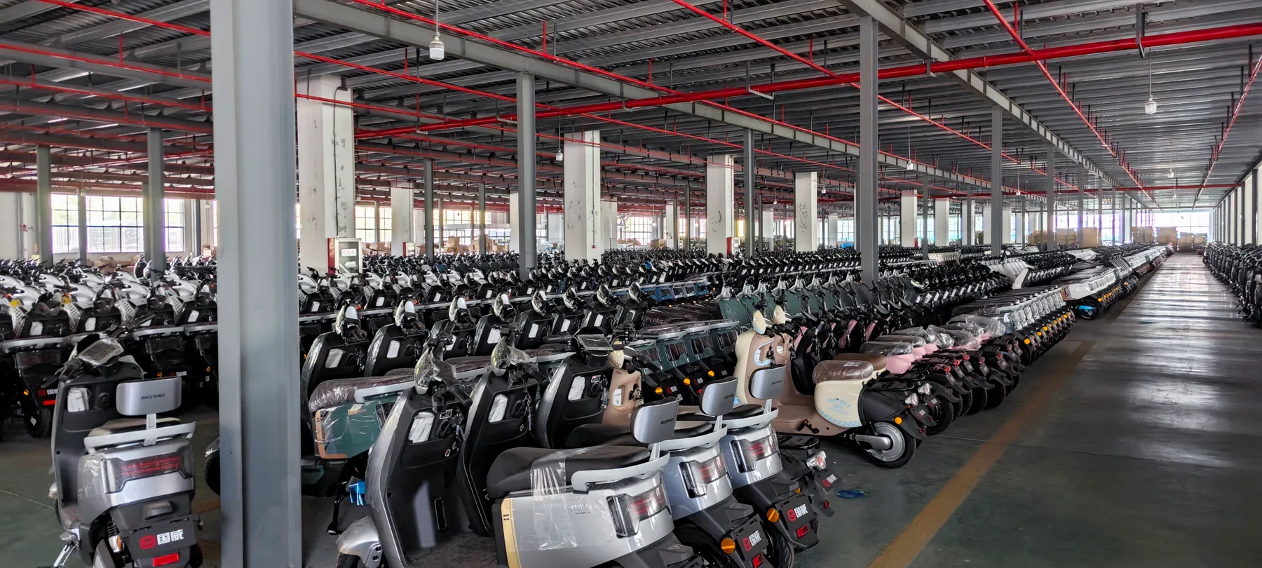 Rows of finished electric two-wheelers inside the company facilities